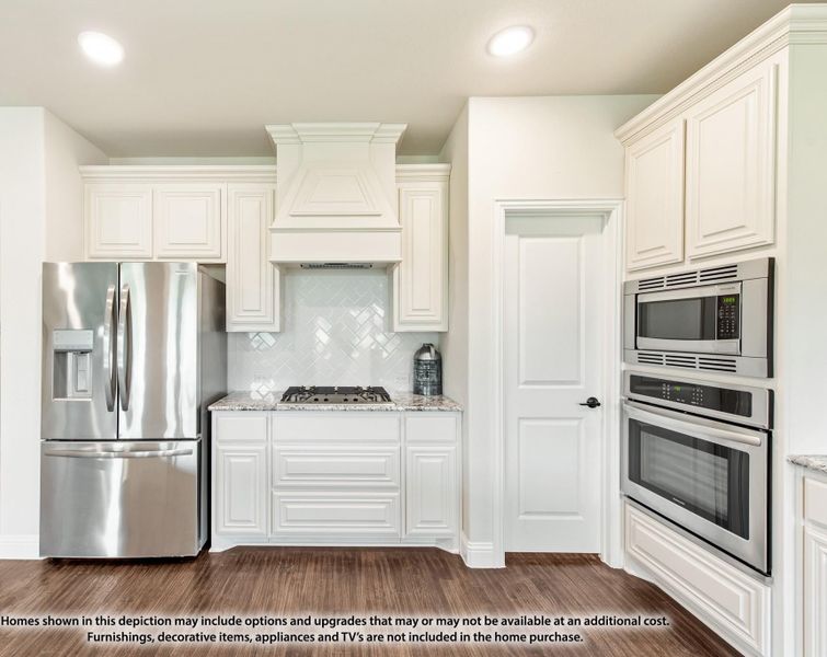 Kitchen with white cabinets, custom range hood, stainless steel appliances, granite countertops, and hardwood floors