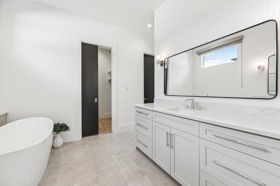 Bathroom featuring vanity, tile patterned flooring, and a tub to relax in