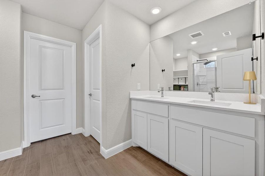 Dual-sink vanity with white cabinetry and integrated sinks, complemented by a large wall-mounted mirror