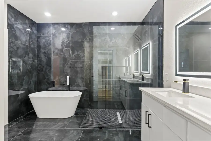 Full bathroom featuring a shower stall, tile walls, a freestanding tub, two vanities, and recessed lighting Full bathroom featuring a shower stall, tile walls, a freestanding tub, two vanities, and recessed lighting