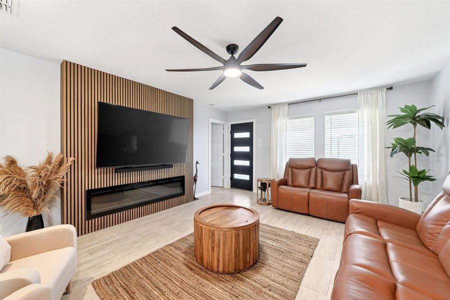 Accent wall with vertical wood slat paneling, integrated electric fireplace, and mounted television