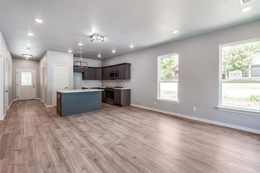 Kitchen featuring sink, stainless steel appliances, light hardwood / wood-style floors, and an island with sink