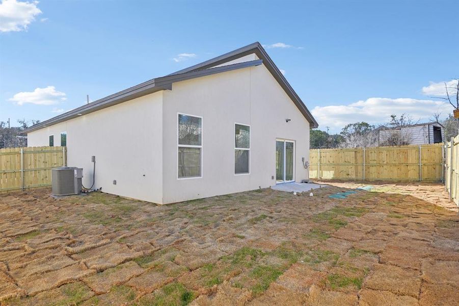 Back of property featuring a fenced backyard, central AC, and stucco siding