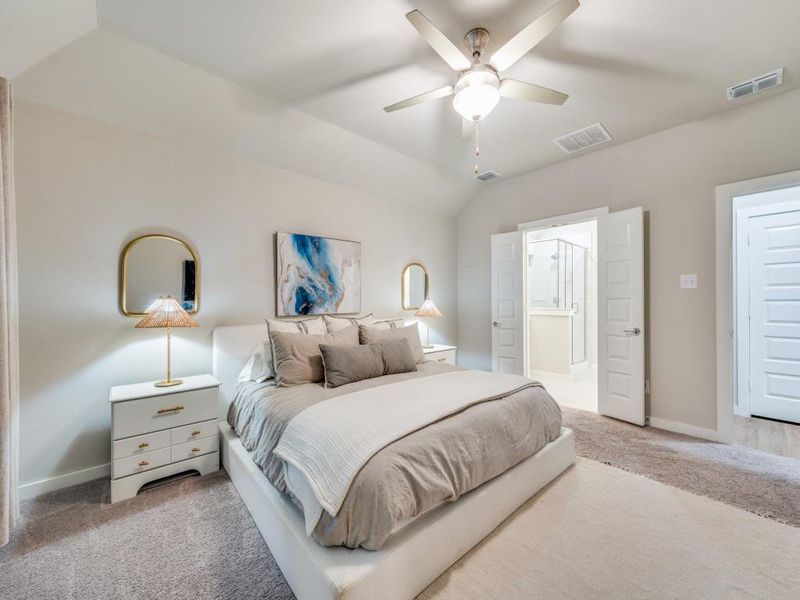 Bedroom featuring carpet, ceiling fan, vaulted ceiling, and ensuite bathroom