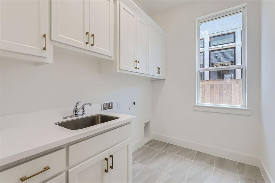 Washroom featuring cabinets, electric dryer hookup, light tile patterned flooring, hookup for a washing machine, and sink