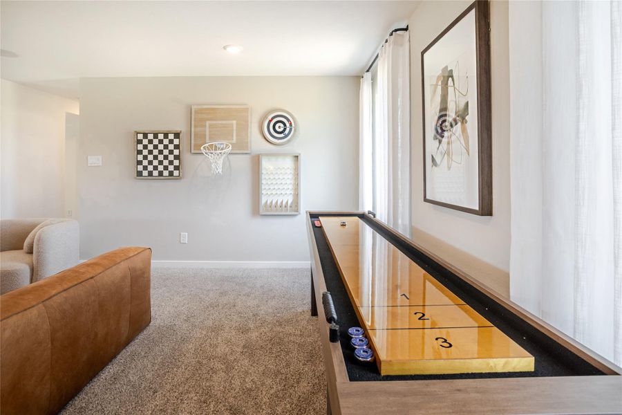 Cozy game room with a shuffleboard table, wall decorations, and comfortable seating. Bright natural light enhances the inviting atmosphere. Cozy game room with a shuffleboard table, wall decorations, and comfortable seating. Bright natural light enhances the inviting atmosphere.
