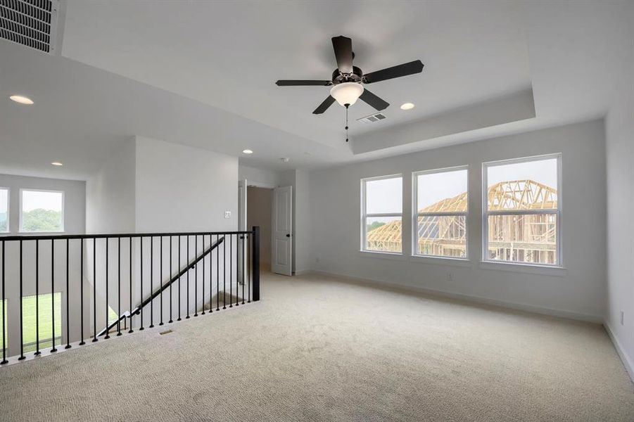 Spacious carpeted room featuring a ceiling fan with light, recessed lighting, and three large windows Spacious carpeted room featuring a ceiling fan with light, recessed lighting, and three large windows