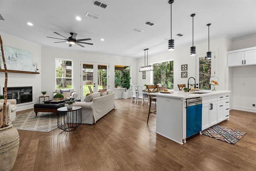 Kitchen featuring white cabinets, sink, decorative light fixtures, and an island with sink Kitchen featuring white cabinets, sink, decorative light fixtures, and an island with sink