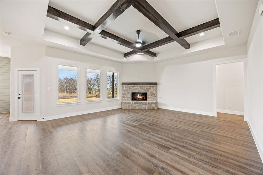 Unfurnished living room featuring coffered ceiling, a fireplace, a ceiling fan, wood finished floors, and recessed lighting Unfurnished living room featuring coffered ceiling, a fireplace, a ceiling fan, wood finished floors, and recessed lighting