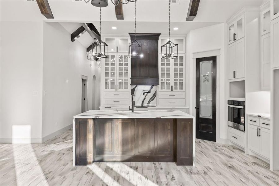 Kitchen featuring glass insert cabinets, dark brown cabinets, white cabinets, an island with sink, and recessed lighting Kitchen featuring glass insert cabinets, dark brown cabinets, white cabinets, an island with sink, and recessed lighting