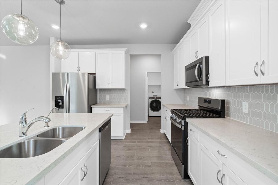 Welcome to the heart of the home, a modern, highly functional kitchen that perfectly balances style and utility. Quartz countertops, complemented by a stylish backsplash, shaker-style cabinets provide ample storage, and the Whirlpool stainless steel appliances are all features of this beautiful kitchen!