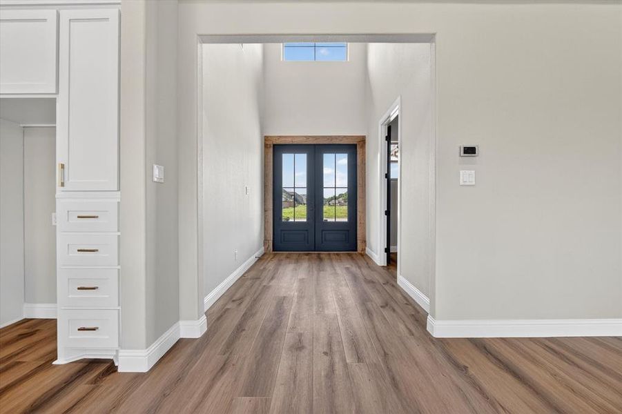 Entryway featuring wood-finish flooring, white baseboards, and a tall ceiling