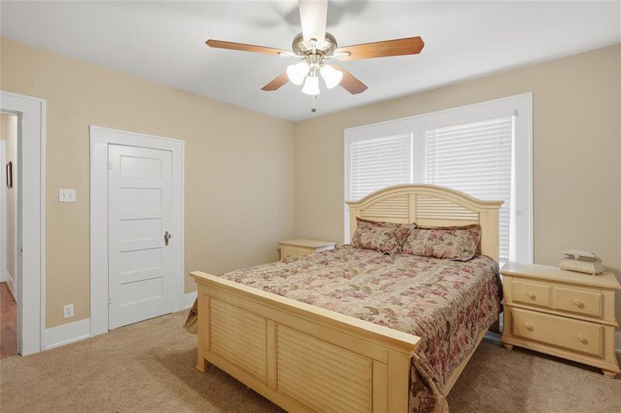 Carpeted room featuring a ceiling fan with light fixture, window with horizontal blinds, and a five-panel interior door