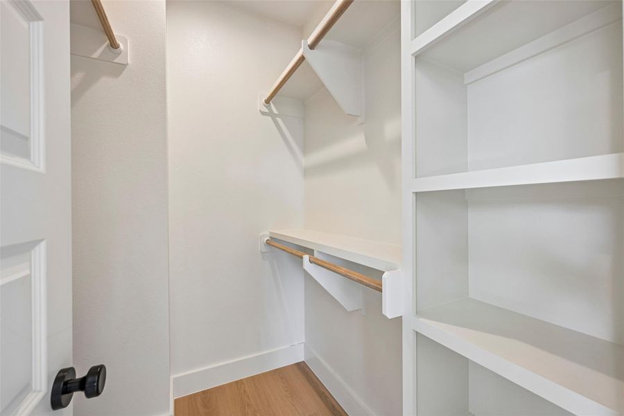 Practical walk-in closet with built in shelving and multiple hanging bars.