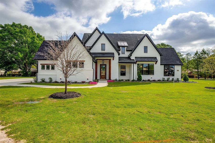 Modern farmhouse style home with a standing seam roof, a front lawn, and roof with shingles Modern farmhouse style home with a standing seam roof, a front lawn, and roof with shingles
