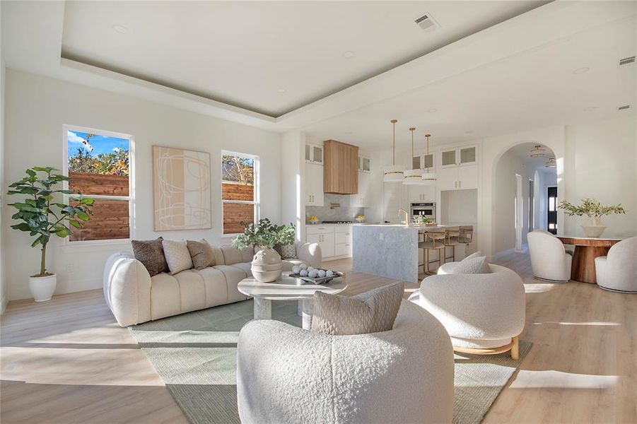 Living area featuring arched walkways, a raised ceiling, and light wood-type flooring Living area featuring arched walkways, a raised ceiling, and light wood-type flooring