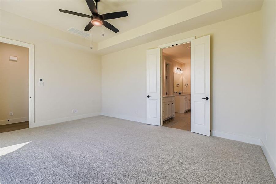 Spare room with light colored carpet, a tray ceiling, and ceiling fan