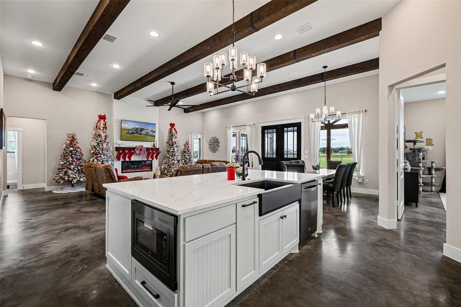 Kitchen with recessed lighting, concrete flooring, light stone countertops, white cabinetry, and black microwave Kitchen with recessed lighting, concrete flooring, light stone countertops, white cabinetry, and black microwave
