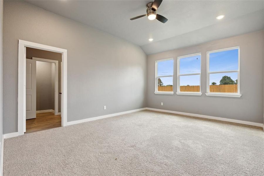 Carpeted spare room with lofted ceiling and ceiling fan