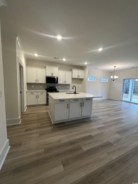 Kitchen featuring white cabinetry, recessed lighting, appliances with stainless steel finishes, a center island with sink, and a chandelier