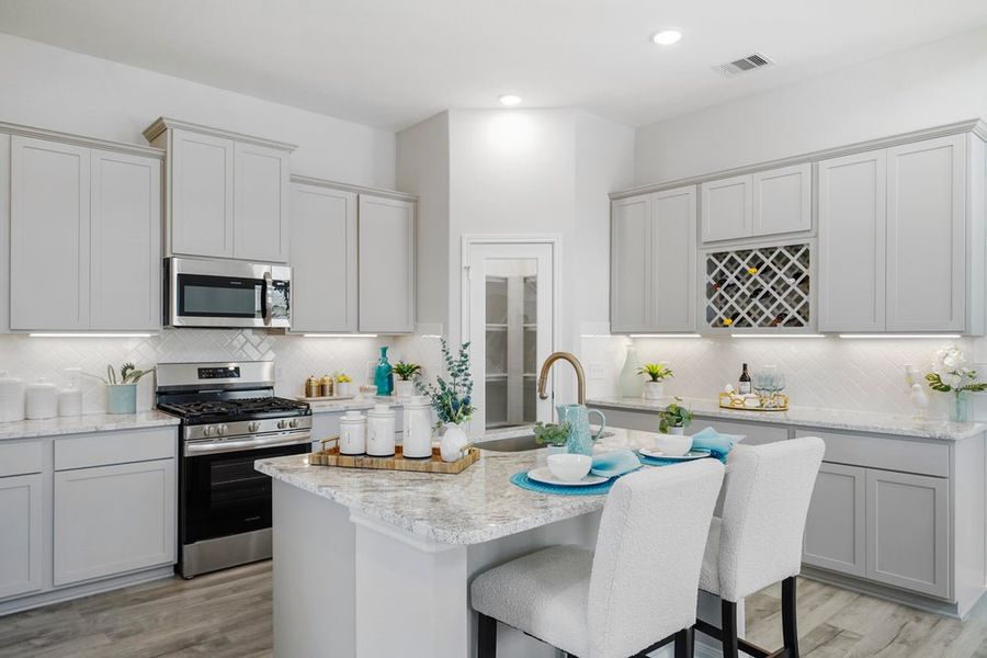 Kitchen with white cabinets, granite island, stainless steel appliances, and built-in wine rack Kitchen with white cabinets, granite island, stainless steel appliances, and built-in wine rack