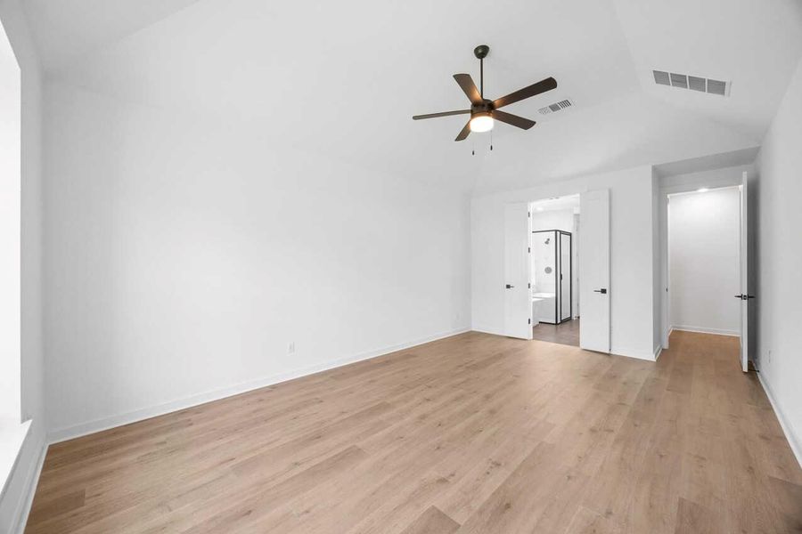 Unfurnished bedroom featuring light wood-style floors, lofted ceiling, a ceiling fan, and ensuite bath Unfurnished bedroom featuring light wood-style floors, lofted ceiling, a ceiling fan, and ensuite bath