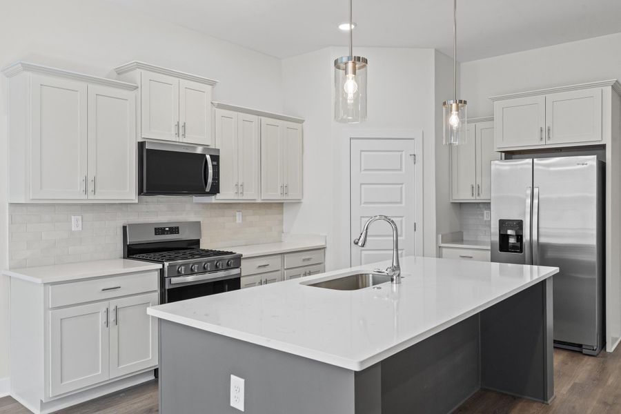 Kitchen featuring stainless steel appliances, dark wood finished floors, backsplash, a center island with sink, and dual tone cabinetry