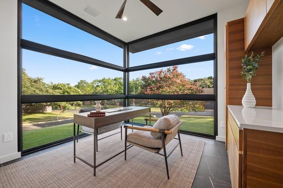 a striking office space awaits, designed to inspire creativity and productivity. Floor-to-ceiling windows bathe the room in natural light, accentuating the contemporary design and highlighting the elegant finishes. Soft, neutral-toned walls reflect sunlight, creating a welcoming atmosphere throughout.