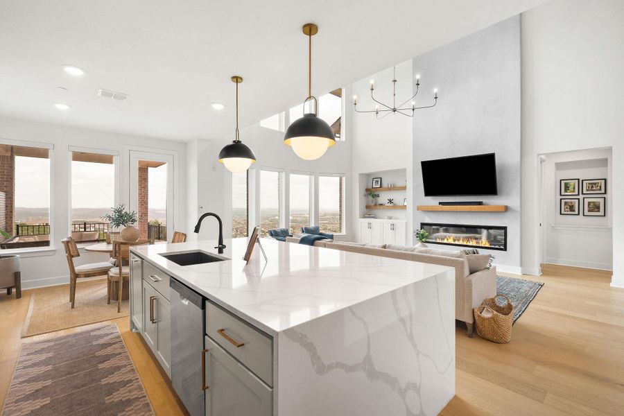 Open-concept kitchen featuring a waterfall island with a built-in sink and pendant lighting Open-concept kitchen featuring a waterfall island with a built-in sink and pendant lighting
