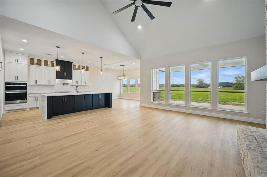 Unfurnished living room with high vaulted ceiling, recessed lighting, light wood finished floors, and a ceiling fan Unfurnished living room with high vaulted ceiling, recessed lighting, light wood finished floors, and a ceiling fan