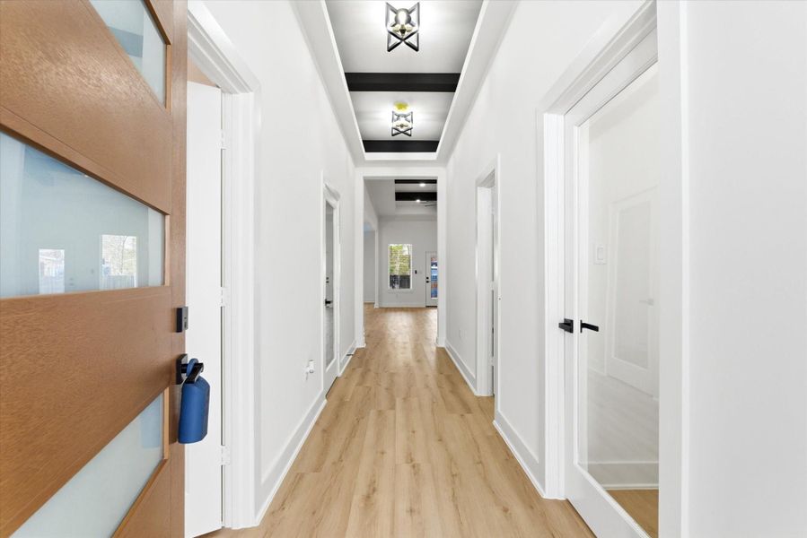 Stunning foyer featuring 12-foot ceilings, luxury vinyl flooring, and ceiling beams with integrated lighting within the tray ceiling.