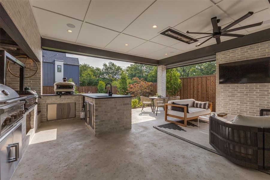 Covered outdoor living area featuring a built-in outdoor kitchen with stainless steel grill, integrated sink, and brick-clad base Covered outdoor living area featuring a built-in outdoor kitchen with stainless steel grill, integrated sink, and brick-clad base