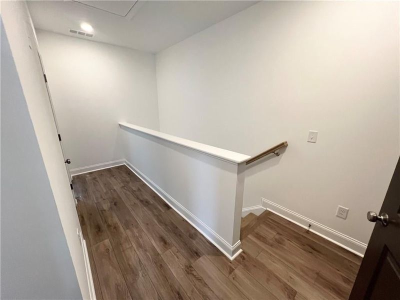Corridor with an upstairs landing and dark wood-style flooring