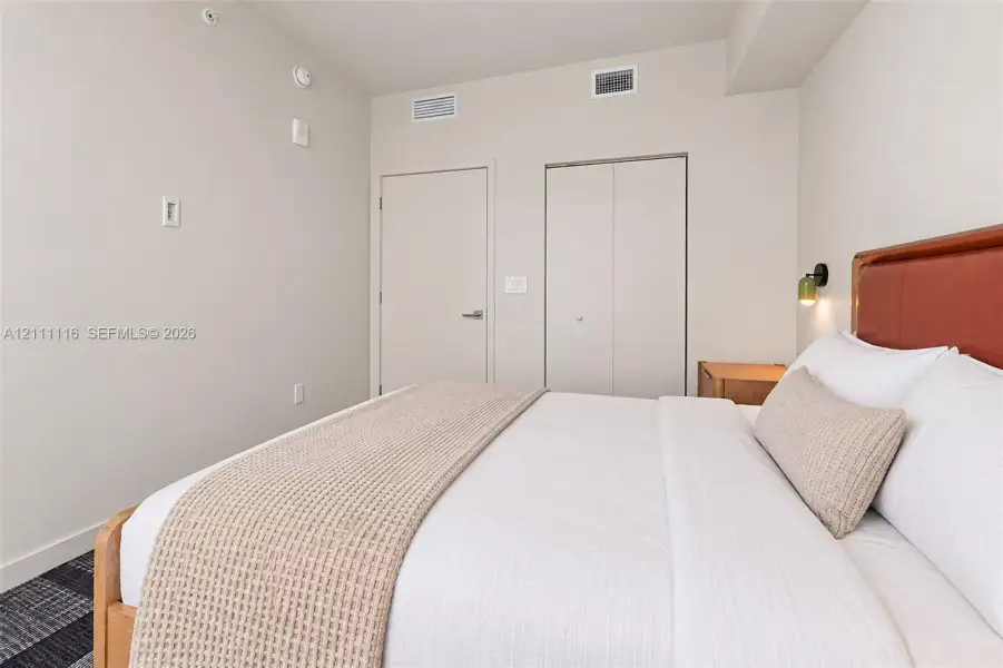Neutral-toned interior featuring patterned carpeting, matte-finish walls, and dual closet access with solid-core swing and bi-fold doors