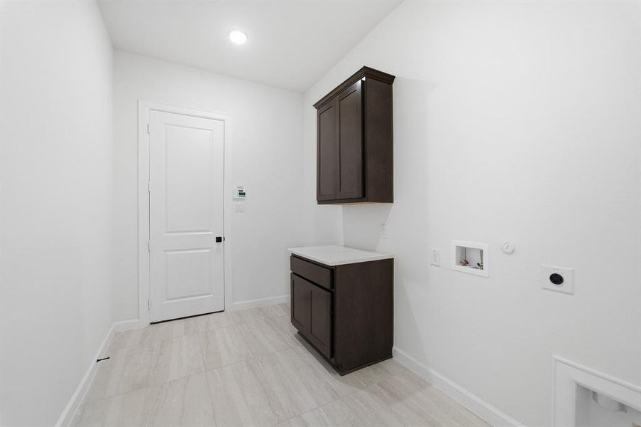Utility room featuring dark wood-finish cabinetry with a light-toned countertop, recessed lighting, and tile flooring