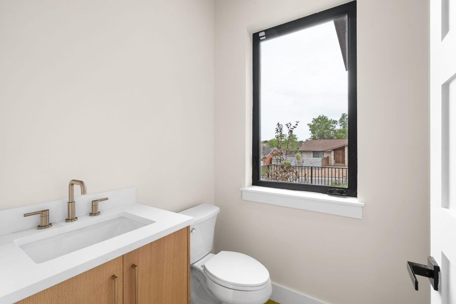 Contemporary vanity with light wood-finish cabinetry, white countertop, and integrated rectangular sink