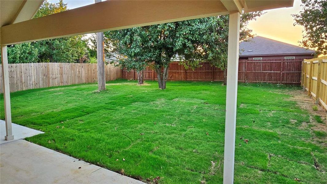 Yard at dusk with a fenced backyard and a patio area