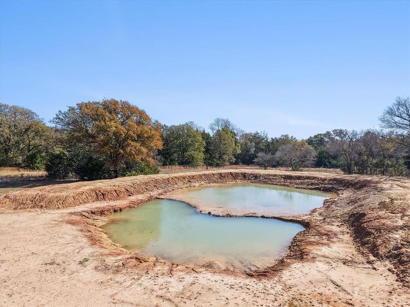 Freshly excavated pond with an irregular shape, surrounded by cleared earth