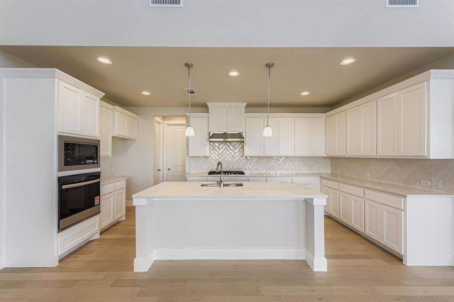 Kitchen featuring appliances with stainless steel finishes, decorative light fixtures, white cabinets, recessed lighting, and backsplash