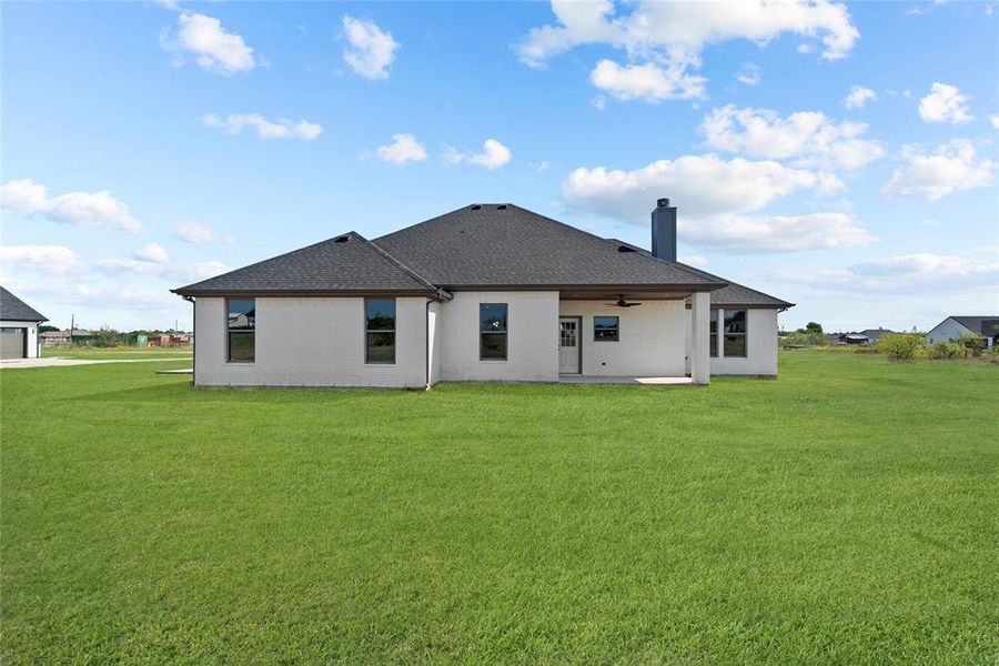 Back of house with a yard and a patio