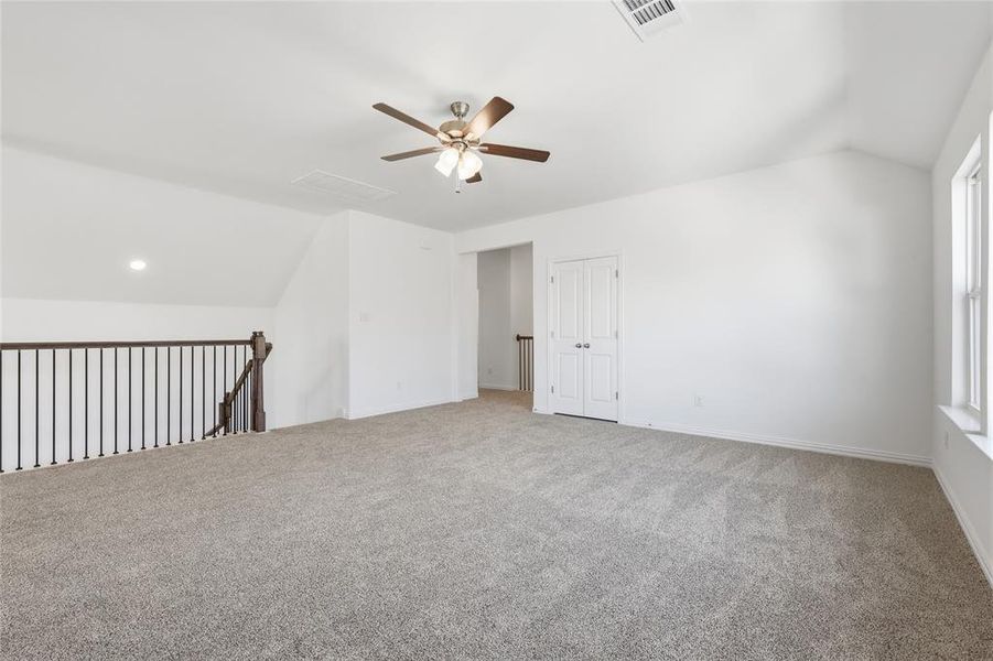 Spare room featuring lofted ceiling, ceiling fan, and carpet