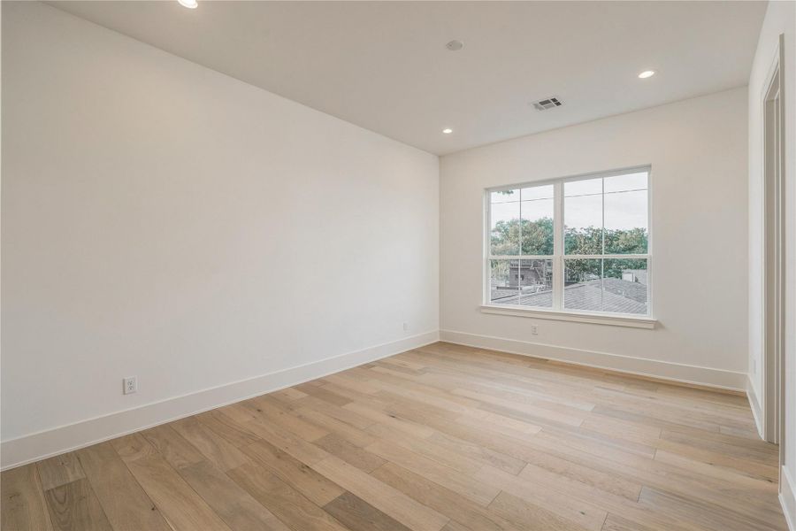 This secondary bedroom offers a bright, versatile canvas, with wide-plank oak flooring and a large window overlooking the backyard.