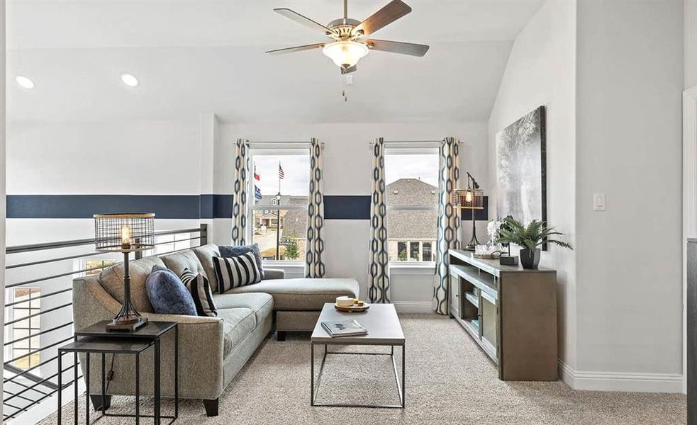 Carpeted living room with ceiling fan and vaulted ceiling