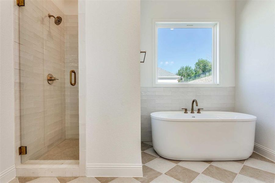 Bathroom featuring a stall shower, a soaking tub, and tile walls Bathroom featuring a stall shower, a soaking tub, and tile walls