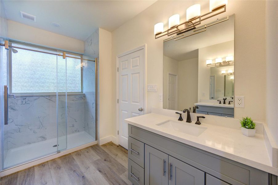 Elegant primary bathroom with modern fixtures, a sleek vanity, and a spacious glass-enclosed shower.