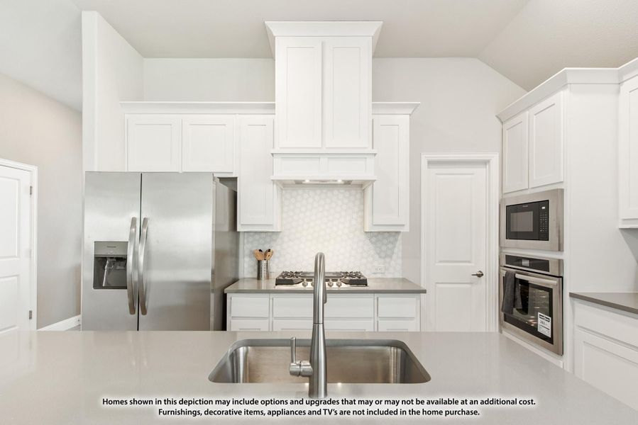 White kitchen with stainless steel appliances, built-in range hood, wall ovens, and island sink with gray countertops White kitchen with stainless steel appliances, built-in range hood, wall ovens, and island sink with gray countertops