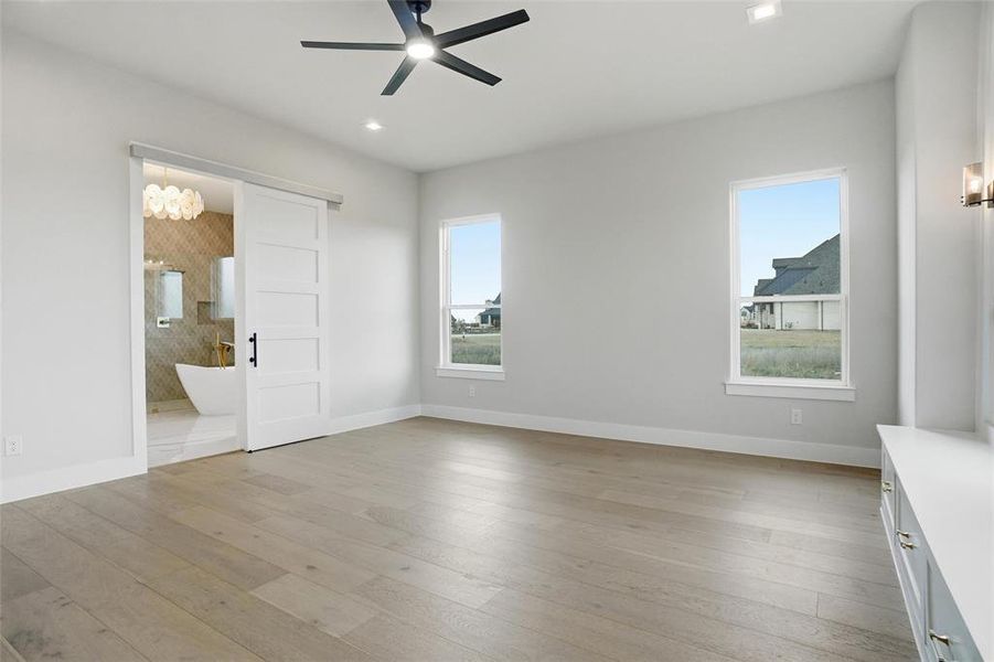 Spacious primary suite with sliding barn door leading to the luxurious primary bathroom.