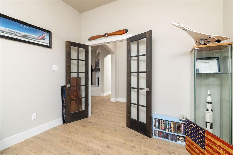 Doorway with arched walkways, wood finished floors, and french doors