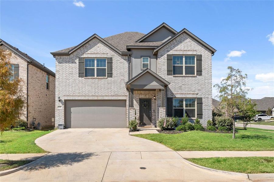 Craftsman-inspired home with a front yard, concrete driveway, brick siding, and an attached garage