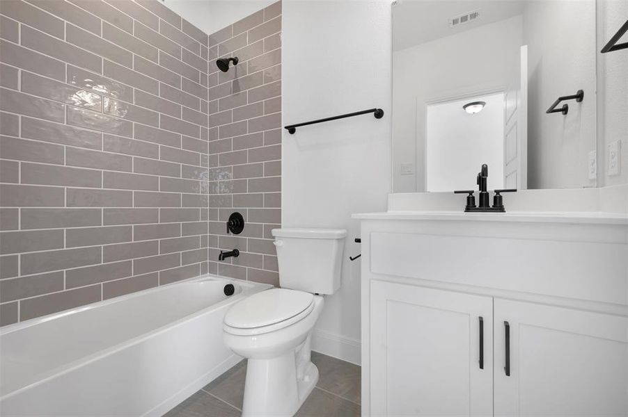 Full bathroom featuring vanity, washtub / shower combination, and dark tile patterned floors
